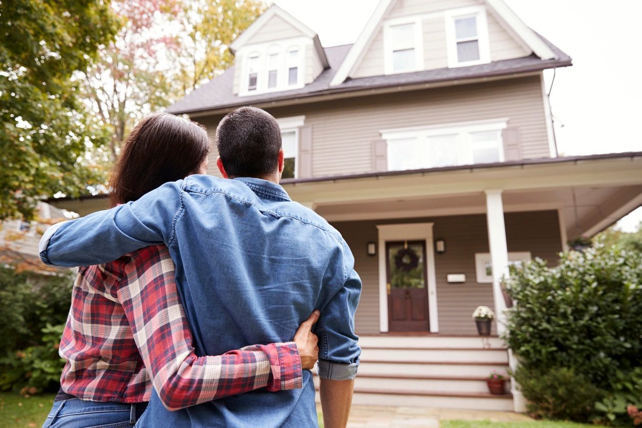 Couple embracing while looking at their new home.