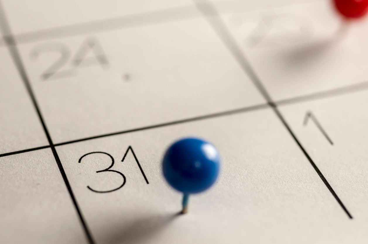 A blue pushpin marking the 31st on a calendar.