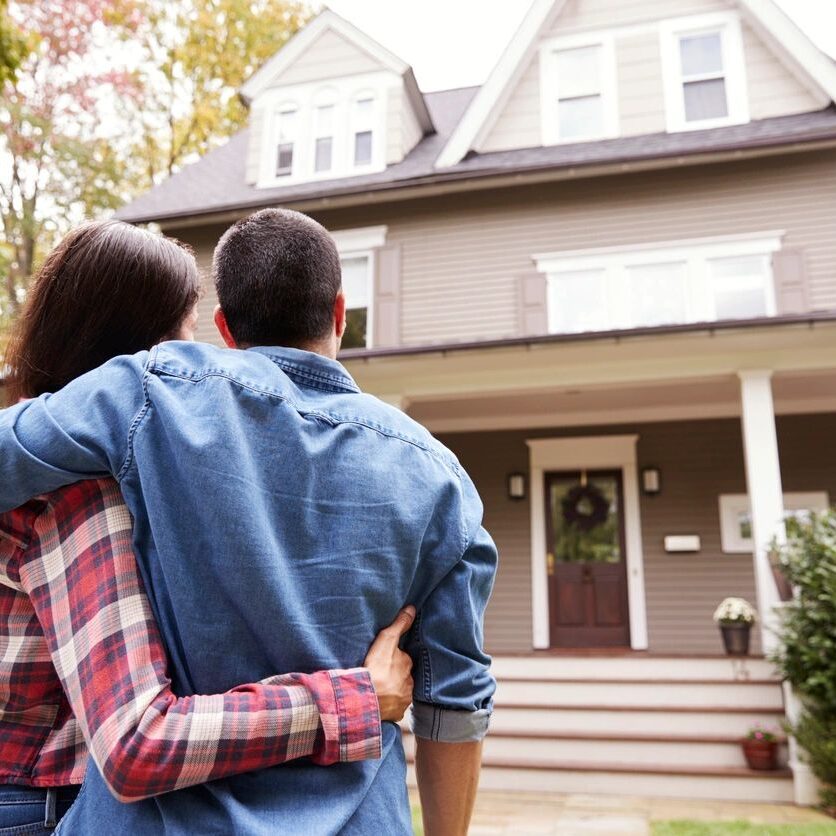 Couple embracing while looking at their new home.
