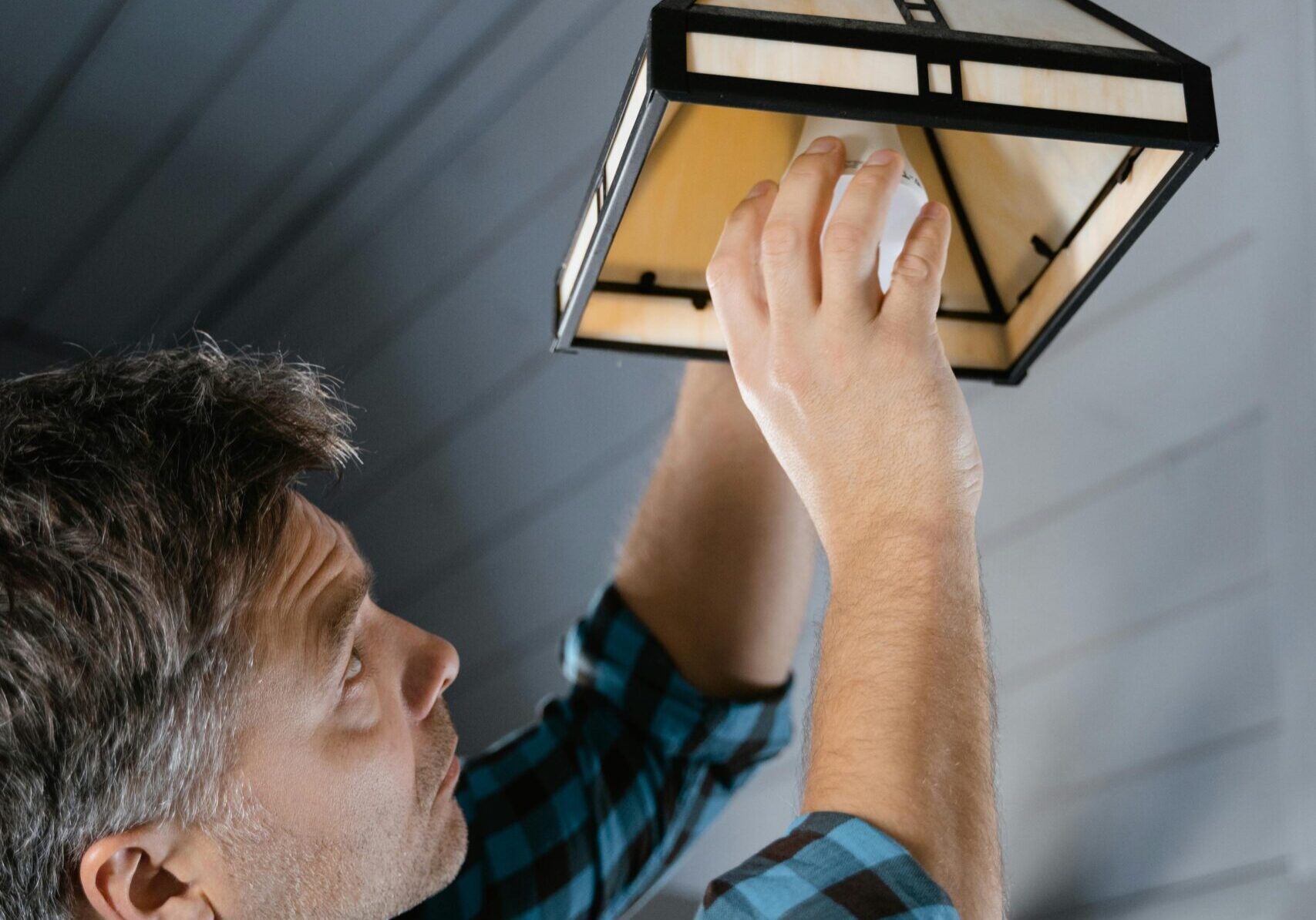 Man replacing a light bulb in an outdoor lantern.